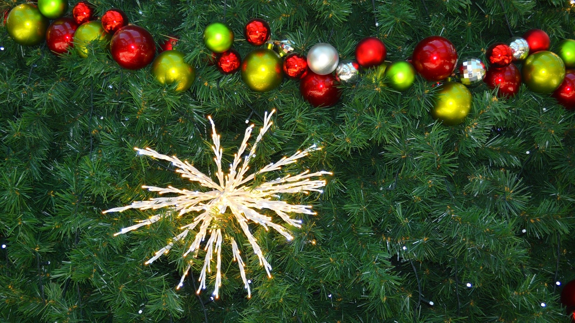 HD Christmas desktop wallpaper featuring a decorated tree with colorful baubles, festive lights, and bright holiday ornaments.