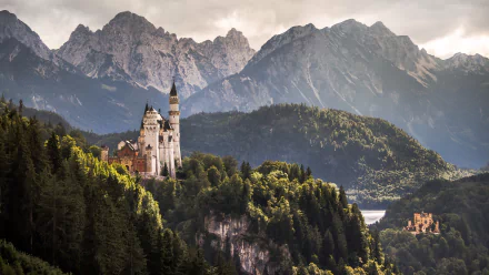 HD PC desktop wallpaper of a man-made castle perched on a forested cliff with misty alpine mountains in the background.