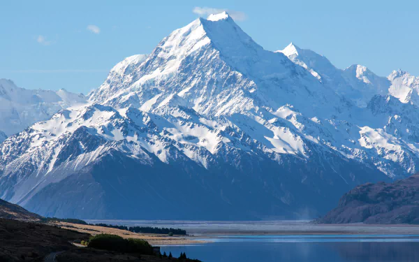 Snow-covered mountain towering over a serene lake, showcasing pristine nature in stunning 4K Ultra HD quality for a striking PC desktop wallpaper and background.