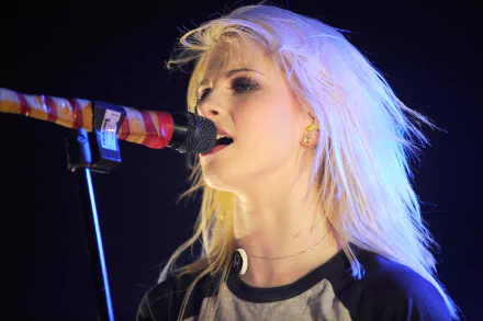HD PC desktop wallpaper showing Hayley Williams singing passionately into a microphone during a live music performance.