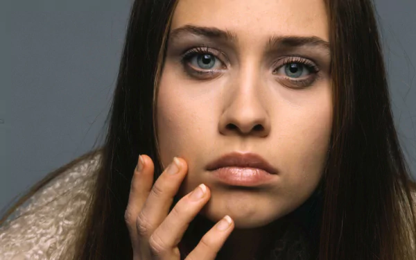 Close-up portrait of a pensive female singer with hand to face, moody tones — music-themed 2K Quad HD PC desktop wallpaper.