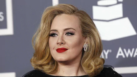 Adele, the renowned British singer, poses gracefully at an award show, showcasing her signature style and elegance in this stunning 4K Ultra HD wallpaper.