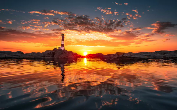 HD desktop wallpaper featuring a lighthouse set against a vivid sunset with reflections on the water.