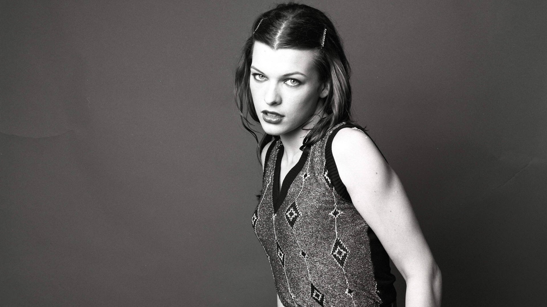 Black and white HD desktop wallpaper featuring celebrity Milla Jovovich in a patterned sleeveless top against a plain background.