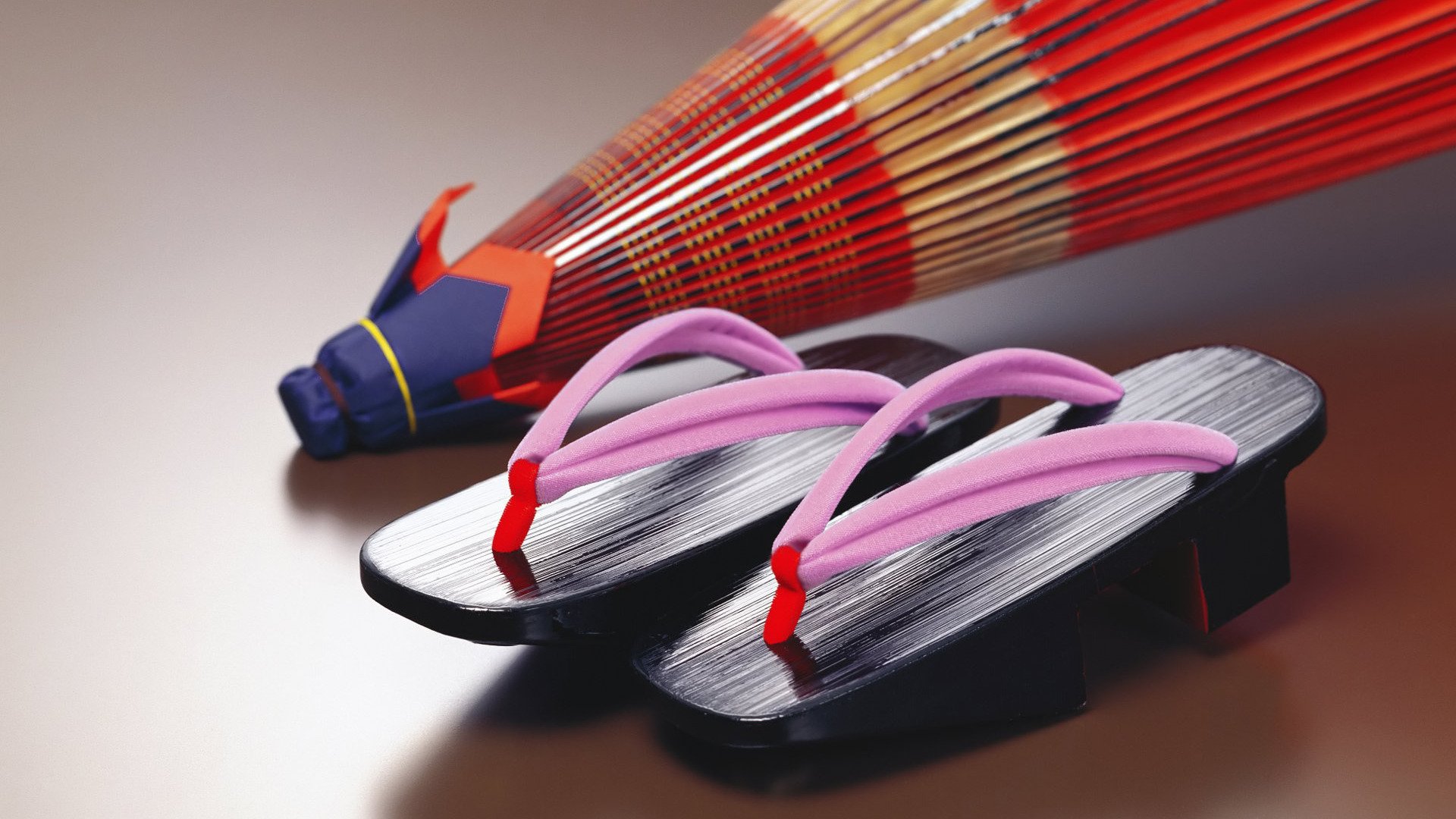 HD desktop wallpaper features traditional Japanese geta sandals paired with a vibrant red oriental umbrella, capturing classic elements of Japanese culture and photography.