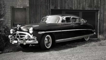 Black-and-white HD PC desktop wallpaper and background featuring a classic Hudson Hornet parked beside a weathered wooden garage.
