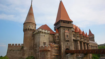 4K Ultra HD image of the man-made Corvin Castle with its distinctive towers and medieval architecture against a blue sky.