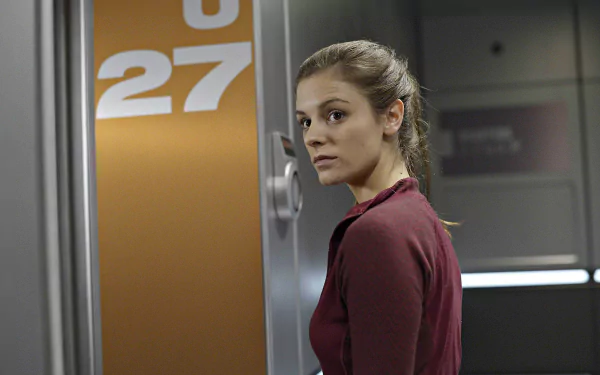 HD wallpaper featuring a woman from the TV show Helix, standing by a door marked with the number 27, suitable as a desktop background.