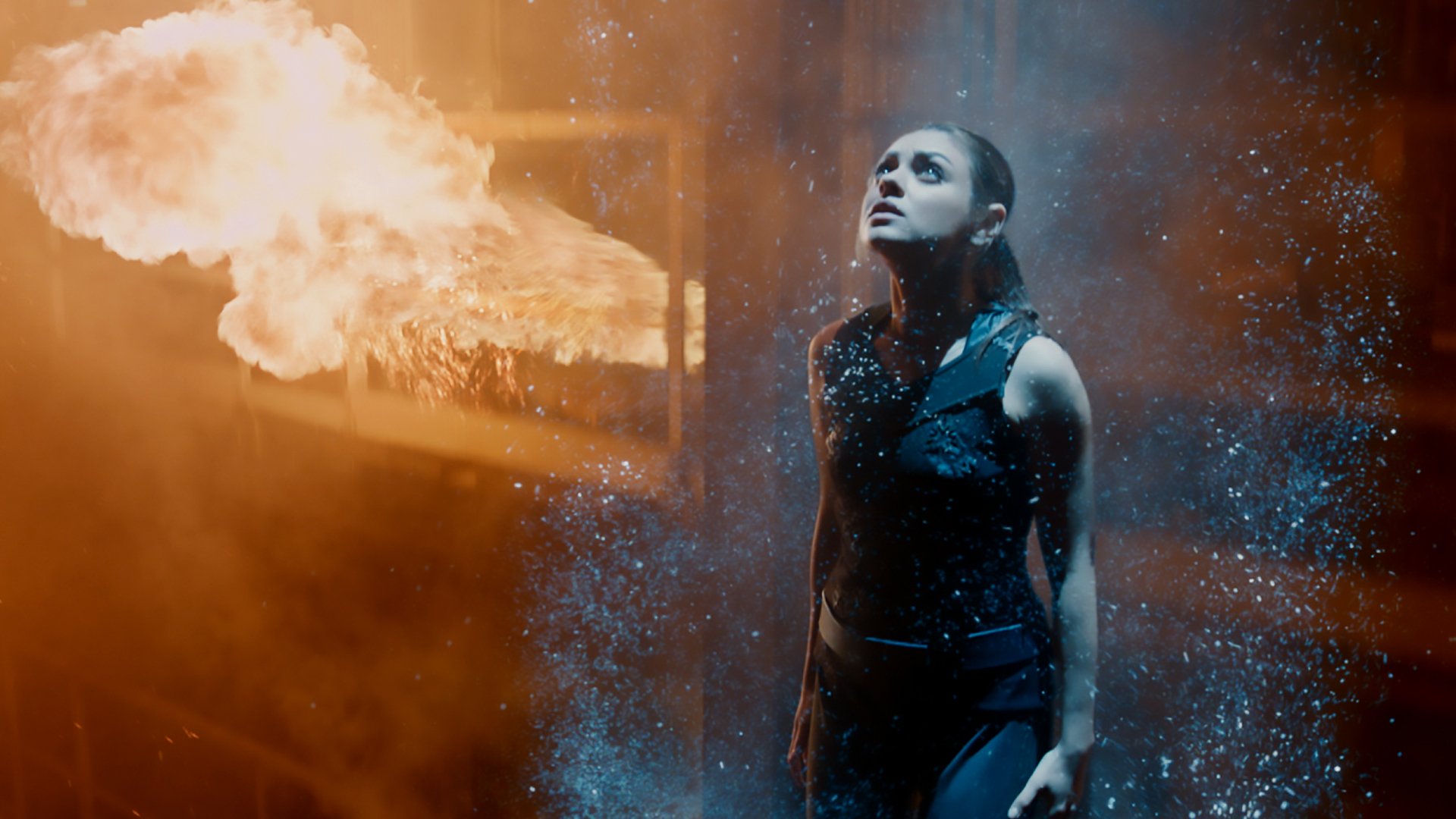HD PC desktop wallpaper featuring Mila Kunis in a dramatic scene from the movie Jupiter Ascending, surrounded by fire and glowing particles.