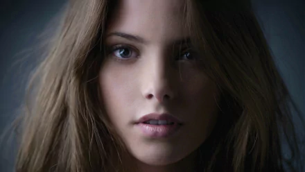 Close-up portrait of a female celebrity with long brown hair and a soft, neutral expression, presented as an HD PC desktop wallpaper/background.