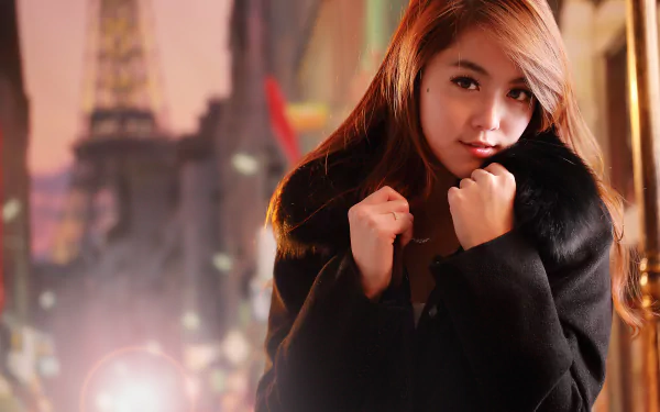 A high-definition wallpaper of a Taiwanese woman named Qiān Yòu wearing a black coat. The background features an urban setting with the Eiffel Tower faintly visible in the distance.