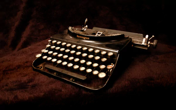 HD desktop wallpaper of a vintage black typewriter on a dark textured surface, showcasing its classic man-made design and keys in sharp detail.