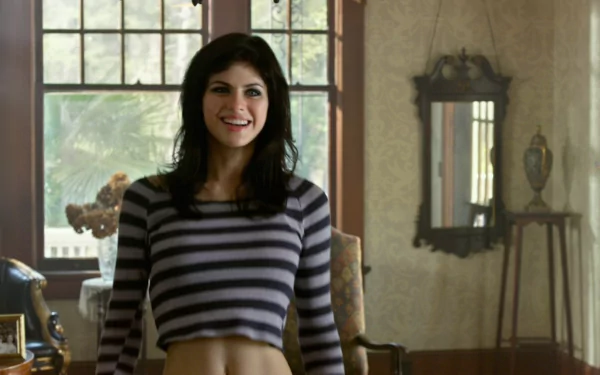 Alexandra Daddario in a scene from *Texas Chainsaw 3D*, smiling while wearing a striped crop top, set in a sunlit room with vintage decor. HD wallpaper background.