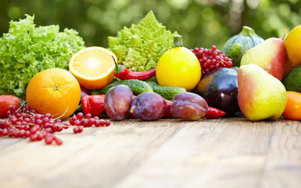 5K Ultra HD PC desktop wallpaper of food: assorted Fruits & Vegetables — oranges, pears, plums, grapes, lettuce on a wooden table, vibrant produce background.