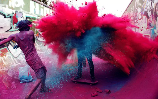 A vibrant scene from the Holi festival, featuring people playfully throwing colored powders in a graffiti-filled skatepark, creating a dynamic explosion of pink and blue hues.