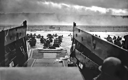 A black and white image depicting soldiers wading ashore from a military boat during D-Day, capturing the intensity and bravery of this historic moment.