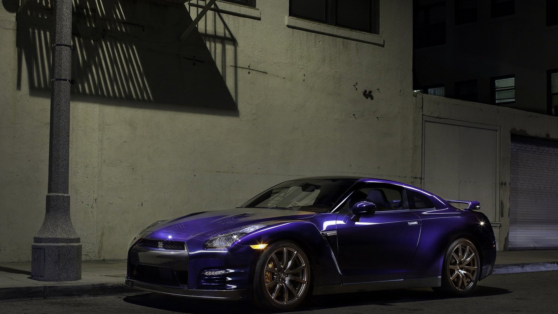 Blue Nissan GT-R parked under a streetlight against an urban wall at night — HD PC desktop wallpaper and background.