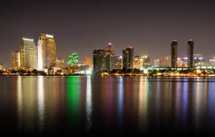 San Diego man-made skyline at night, illuminated high-rises reflected in calm water — HD PC desktop wallpaper/background.