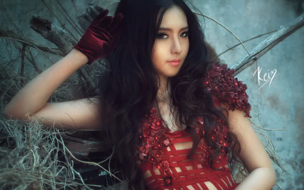HD desktop wallpaper featuring an Asian woman, identified as Mitu Kat, posing with long, dark hair and a red glove. The scene has a rustic background with dried branches and hay.