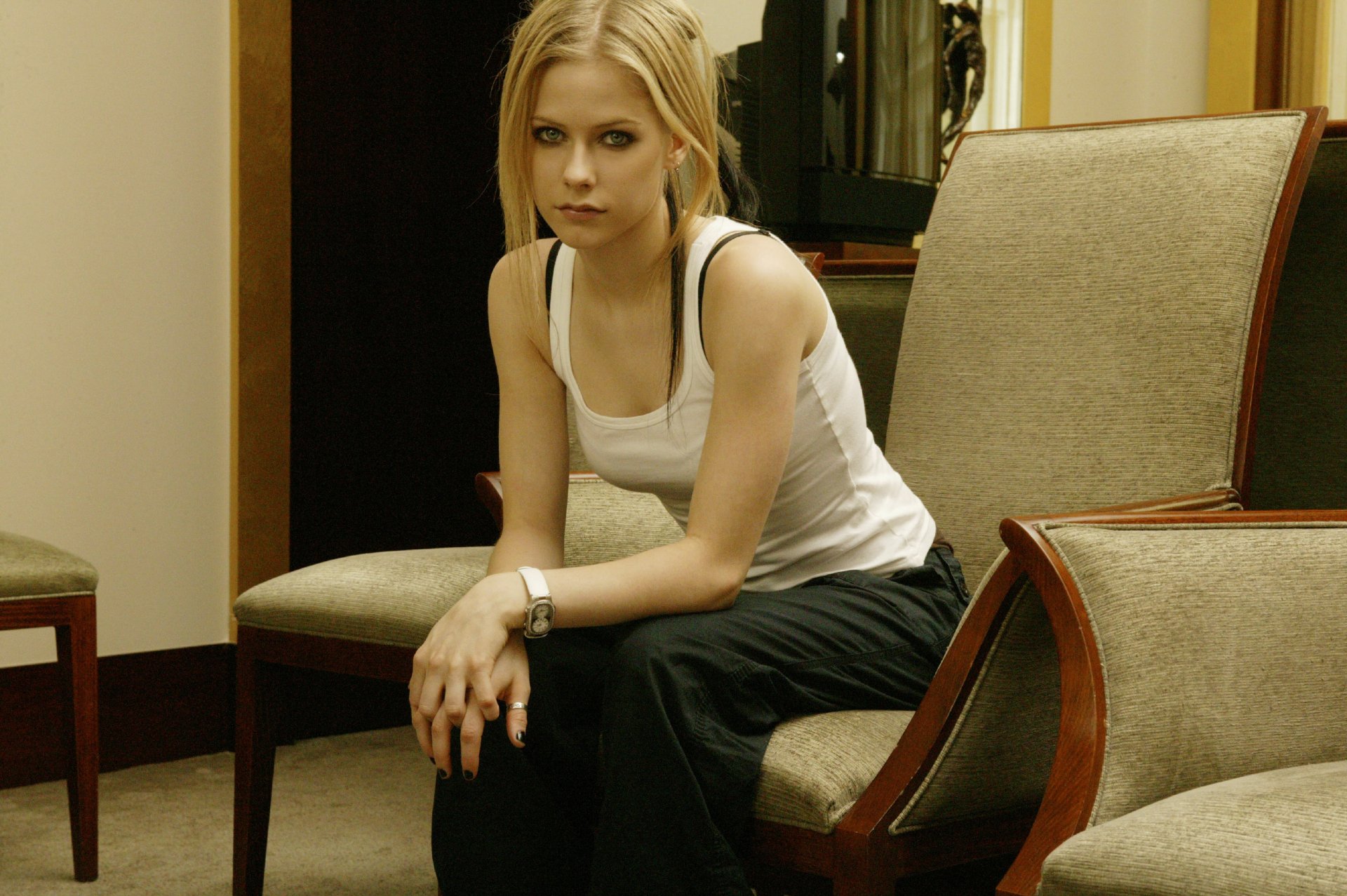HD PC desktop wallpaper featuring Avril Lavigne seated in a room, showcasing a casual music-themed portrait.