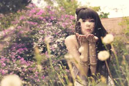A woman with long hair playfully blows dandelion seeds in a vibrant garden filled with flowers, capturing the essence of spring in Pretoria, Africa.