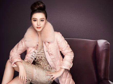 A striking HD wallpaper featuring Chinese actress Fan Bingbing, showcasing a stylish coat with a fur collar and an elegant dress, set against a rich, dark background.