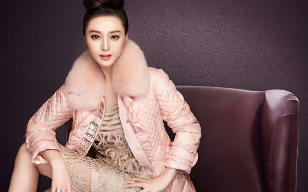 A striking HD wallpaper featuring Chinese actress Fan Bingbing, showcasing a stylish coat with a fur collar and an elegant dress, set against a rich, dark background.