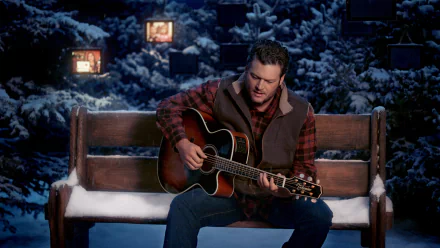 Blake Shelton playing acoustic guitar on a snowy bench, set against a wintery, country music-themed HD desktop wallpaper background.