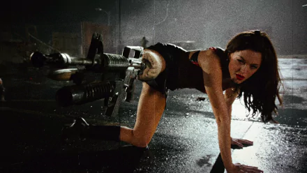 HD PC desktop wallpaper featuring a scene from the movie Planet Terror, showing a woman with a gun prosthetic leg in a dark, intense setting.