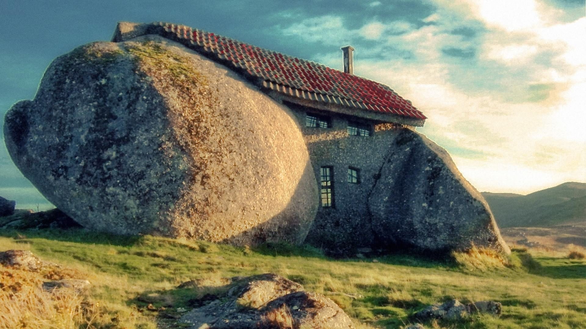 A unique house integrated with large rocks, surrounded by nature, captured in high definition, making it an eye-catching desktop wallpaper and background.