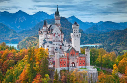 A beautiful HD desktop wallpaper featuring Neuschwanstein Castle amidst the vibrant fall landscape of Bavaria, Germany, with majestic mountains in the background.