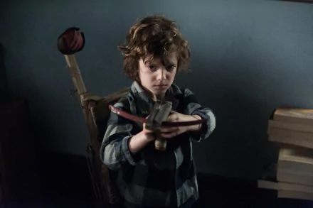 Noah Wiseman as a tense child aiming a toy gun in a dark, moody scene from the movie The Babadook, rendered in 4K Ultra HD for PC desktop wallpaper.