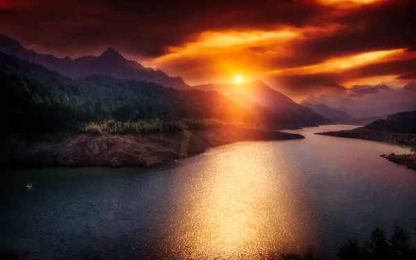 Sunset glow over a mountainous landscape in Catalonia, Spain, with clouds reflecting on a calm river, captured in stunning HD for a desktop wallpaper background.