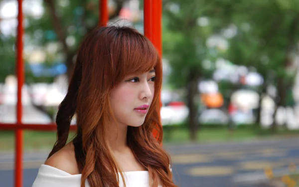 Portrait of a Taiwanese woman with long hair, captured outdoors in 4K Ultra HD, showcasing natural beauty and a serene expression against a blurred urban background.