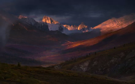 HD desktop wallpaper of the Yukon tundra at sunrise, showcasing rugged Canadian mountains bathed in warm morning light beneath a dramatic sky.