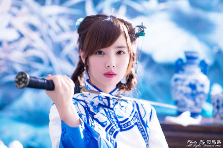 A woman in traditional Taiwanese costume holds a sword with tears in her eyes, set against a serene backdrop. This striking 4K Ultra HD image captures a moment of intensity and grace.
