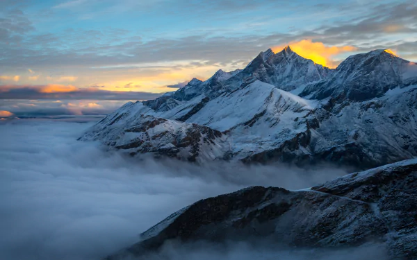 A breathtaking view of the Swiss Alps, shrouded in fog with peaks rising above the clouds, illuminated by a soft sunset glow, creating a serene mountain landscape.