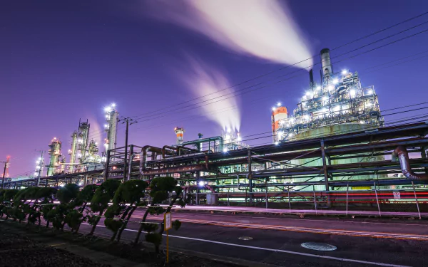 A 4K Ultra HD image of an industrial factory in Yokohama, Kanagawa Prefecture, Japan, with smoke rising against a twilight sky, showcasing man-made structures and bright lights.