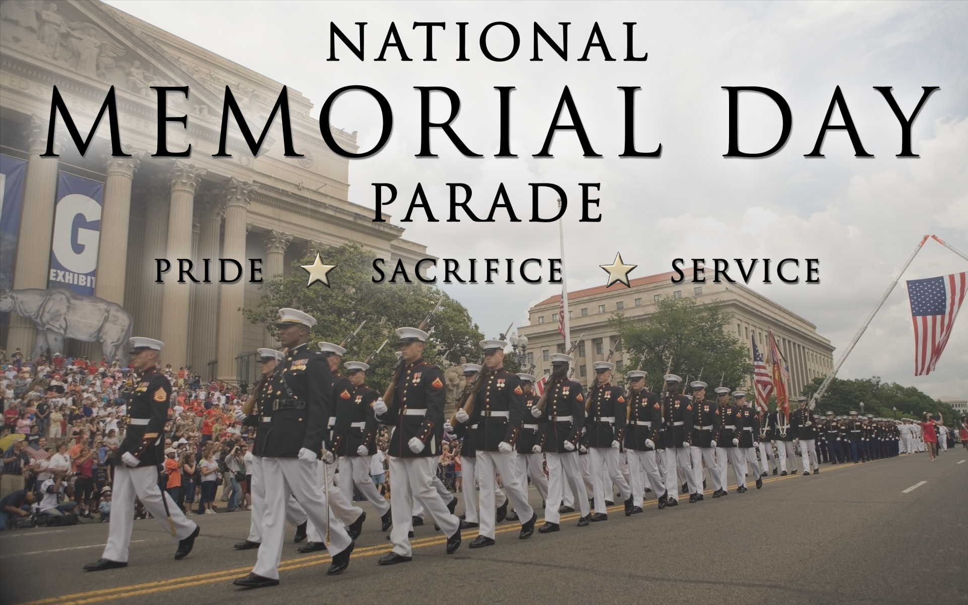Memorial Day holiday 2K Quad HD PC desktop background: uniformed servicemembers marching in a National Memorial Day parade past crowds, flags and classical buildings.