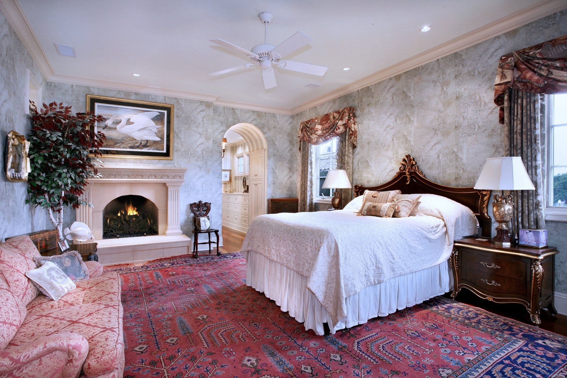 A 4K Ultra HD interior view of a stylish bedroom featuring classic furniture, a fireplace, ornate curtains, and a large rug, creating a cozy and elegant man-made room.