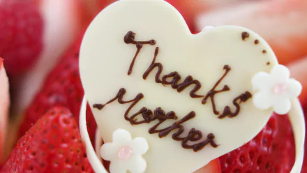 HD desktop wallpaper featuring a heart-shaped white chocolate with Thanks Mother written on it, surrounded by strawberries, celebrating Mother's Day.
