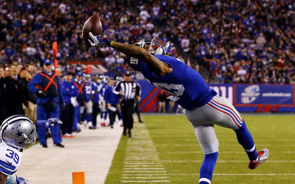 A dramatic capture of a New York Giants player leaping to make a spectacular catch during a game, showcasing the excitement of sports in a vibrant stadium setting.