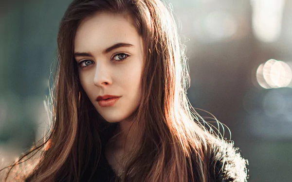 A captivating portrait of a woman with long hair, featuring soft bokeh effects that enhance her striking features, making it a stunning HD background.