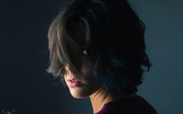Close-up 4K Ultra HD wallpaper of a woman with tousled hair partially covering her face, capturing a mysterious and moody atmosphere.