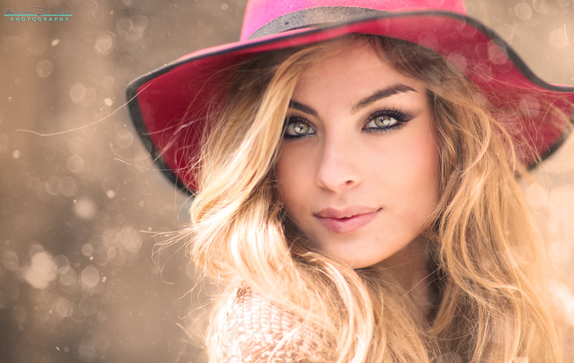 A woman with long, wavy hair and striking eyes wears a pink hat, set against a soft bokeh background. This 4K Ultra HD image captures an enchanting and dreamy portrait.