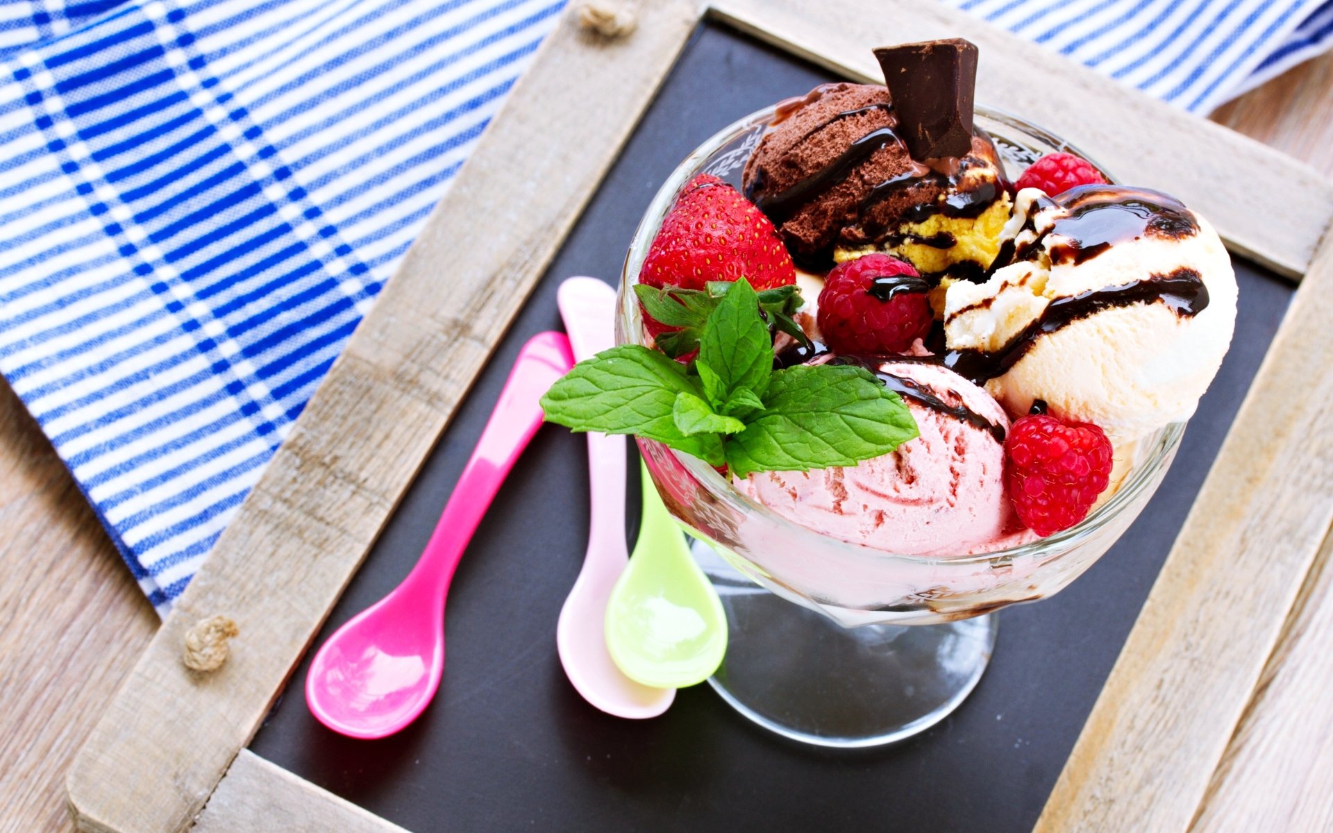 A vibrant 4K Ultra HD dessert wallpaper featuring a glass bowl with scoops of ice cream, fresh strawberries, mint leaves, and chocolate drizzle on a wooden tray.