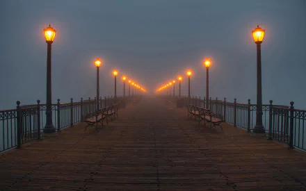 HD wallpaper featuring a misty evening at Pier 7 in San Francisco, with illuminated lamps lining the wooden pier.