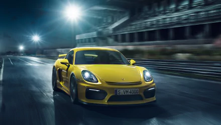 Yellow Porsche Cayman GT4 speeding on a racetrack at night, showcased as an HD PC desktop wallpaper and background.