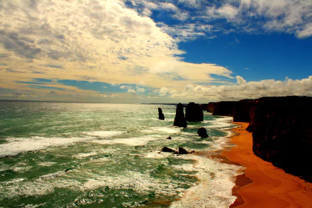 A stunning 4K view of The Twelve Apostles limestone stacks along the rugged coastline of Victoria, Australia, under a partly cloudy sky with vibrant ocean waves.