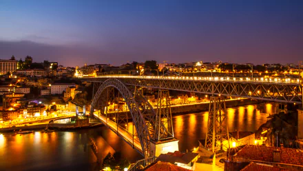 5K Ultra HD wallpaper: Luís I Bridge in Porto, Portugal — a man-made arched bridge lit over the Douro River at night with glowing city lights.